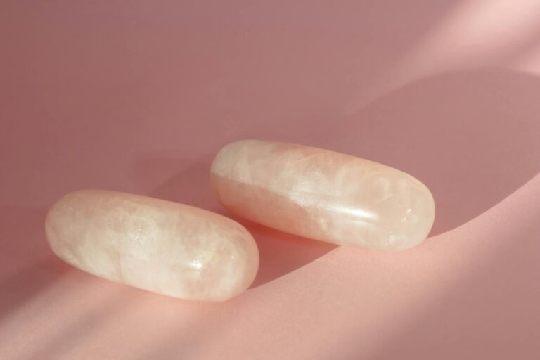Close-up of elegant rose quartz stones on a soft pink surface with gentle shadows.
