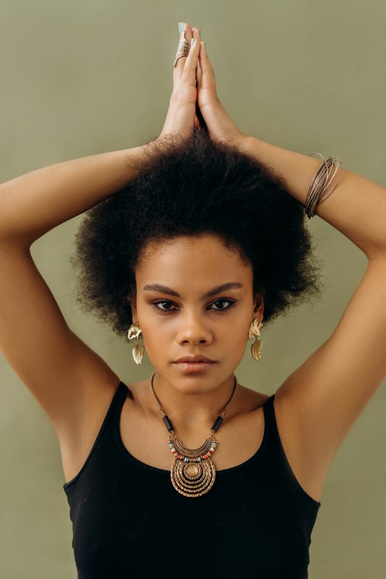 Portrait of an elegant woman with raised arms, adorned with stylish jewelry, exuding confidence and grace.